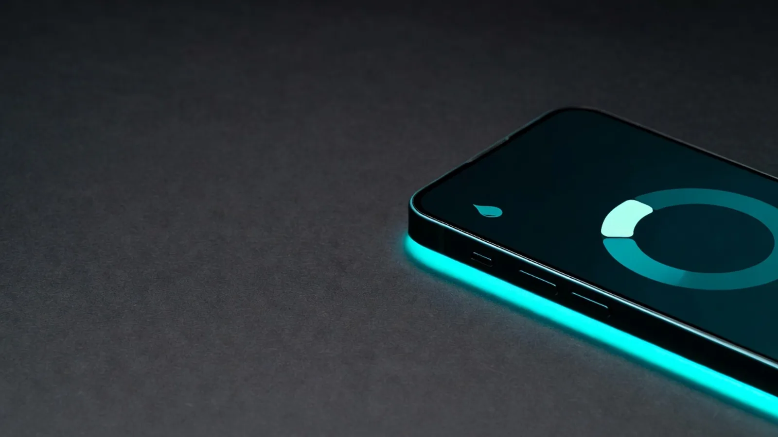 A smartphone lying flat showing a minimal dual-ring hydration dial in teal and cyan, on a dark matte surface under clinical studio lighting.
